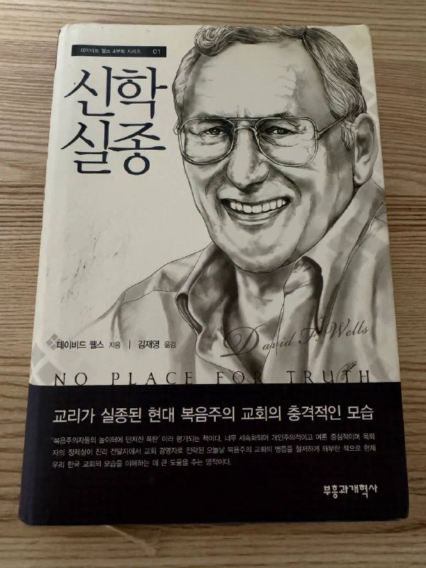 나무 탁자 위에 놓인 『신학실종』 표지. 인물 초상과 데이비드 웰스 지음, 김재영 옮김, 부흥과개혁사라는 표기가 보인다.